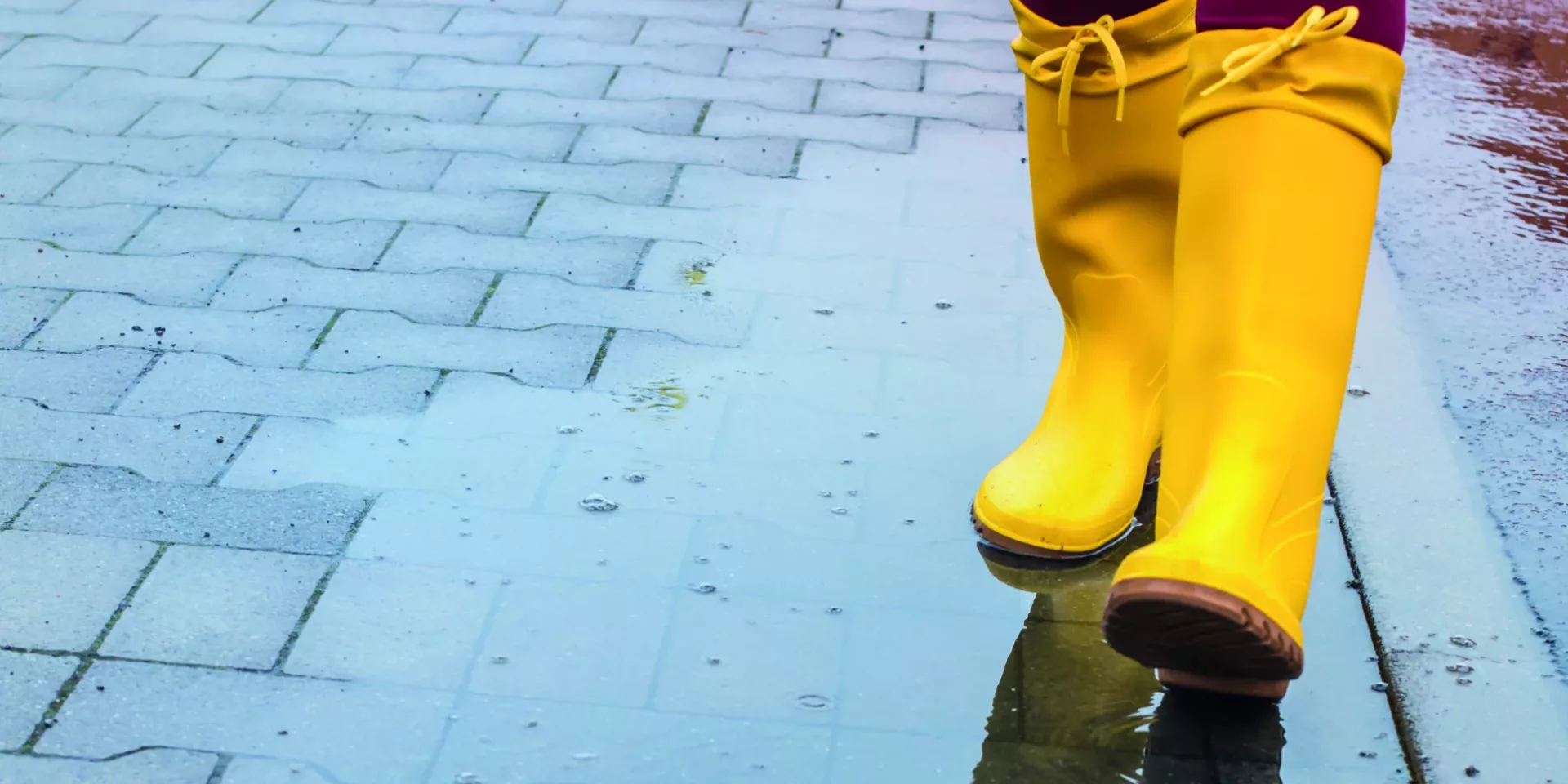 Gelbe Gummistiefel in einer Regenpfütze